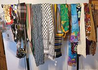Various ladies scarves and shawls hanging on a rack showing diverse patterns and colors