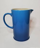 Front view of blue ombre Le Creuset pitcher showing handle and spout with tall cylindrical shape.