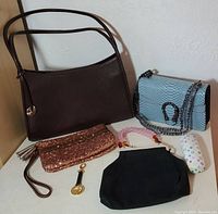 All handbags and accessories shown together to display full lot contents including brown leather shoulder bag, blue crocodile pattern handbag, Juicy Couture wristlet clutch, black handbag, handbag tag, and glasses case.