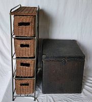 Front view of the two brown wicker storage pieces together, showing the metal framed four-drawer wicker tower on the left and the lidded cube trunk on the right.
