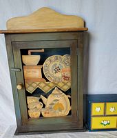 Large wooden tea and coffee cabinet with decorative front panel and glass door