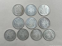 Top view image of 10 Canadian 50 cent coins laid out flat, showing the reverse side with Canadian coat of arms and crown.