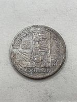 Reverse side of the 1958 Canada silver dollar coin showing the Northwest Coast Native totem pole design, dates 1858-1958, and inscriptions 'CANADA' and 'BRITISH COLUMBIA'.