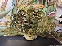 Full front view of unfolding fan-shaped brass screen