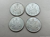 Top side of four Canadian 50 cent silver coins showing detailed coat of arms, two dated 1965 and two dated 1966.