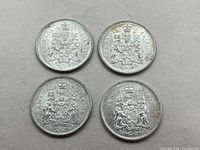 Top-down image of the reverse side of four Canadian 50 cent coins showing the coat of arms.