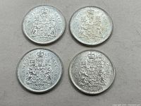 Four Canada silver 50 cent coins laid out flat on a grey surface. Coins dated 1936 and 1965 with visible wear and patina.