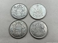 Four Canadian silver 50 cent coins showing front designs, including three dated 1958 and one dated 1965.