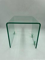 Front view of a clear glass side table showing U-shape and transparent panels.