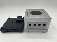 Front view of silver GameCube console and black Game Boy Player attachment side by side