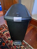 Front view of black pet-proof garbage bin with lid and foot pedal
