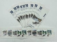 Nine unopened Canada stamp booklets fanned out showing the front cover with dragonfly and Heritage River text.