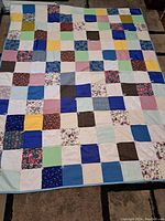 Full view of the vintage patchwork quilt laid out flat showing the multicolored square patches of fabric.