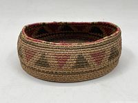 Front angled view of oval woven basket showing geometric painted motif on the side and rim