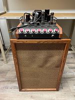 Front view of wooden speaker cabinet with amplifier placed on top