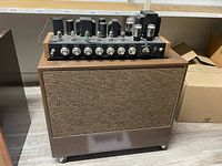 Amplifier head seated atop brown vinyl speaker cabinet showing overall lot