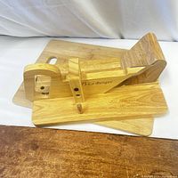 Photo showing the wooden cheese slicer on top of two different wooden cutting boards showcasing the brands and engraving.