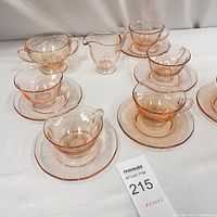 Photo showing six saffron colored cups and matching saucers, plus creamer and sugar bowl on white cloth.