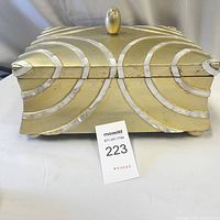 Front view of the large wooden box showing golden color with decorative silver arcs and a domed lid handle.