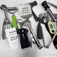 Photo showing a group of kitchen utensils including ice cream scoop, peeler, spatula, corkscrew, ladle, citrus reamer, pizza cutter, tongs, and zester.