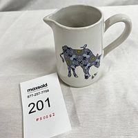 Front view of the ceramic pitcher showing cow and chicks illustration.