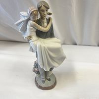 Front view of the Lladro wedding couple figurine, showing groom carrying bride wearing veil and gown.