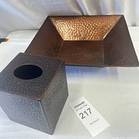 Photo showing the square hammered metal tissue box cover next to the square hammered metal decorative dish on a white backdrop.
