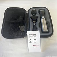 Hair groomer and three attachments in molded carrying case with power adapter and accessories in mesh pockets.