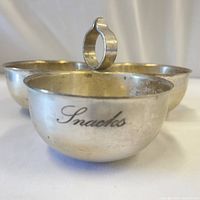 Close-up of one bowl showing 'Snacks' engraving and overall silver tone metal finish.