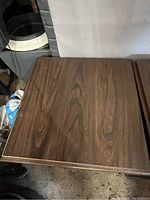 Top view of one side table showing brown wood grain surface with minor wear marks.