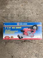 Boxed King Canada belt sander showing brand, model number, and product image of the red and black sander.
