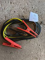 Photo shows coiled booster cables with coloured insulated wiring and red and black clamps.