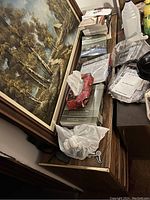 Front angle view of the wooden dresser with gold trim, showing four drawers and cluttered top surface with papers and books.