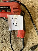 Photo showing the full side view of the red King Canada electric drill with seller's tag attached.