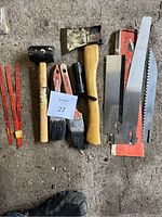 Image showing all tools arranged on concrete floor including mallet, pliers, brushes, hacksaw blades, and flashlight