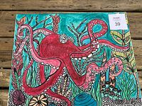 Front view of the octopus themed painting laid on a wooden floor, showcasing the colorful sea life design.