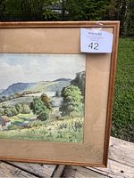 Full view of the painting in wooden frame showing landscape with hills, trees, and house.