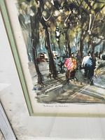 Close-up photo of first watercolor painting showing two cyclists on a tree-lined street, signed by the artist.