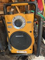 Front view of yellow Magnasonic radio showing speaker, tuning dial, and controls with black protective frame and handle.