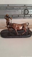 Full view of bronze bullfighter and bull statuette on marble base from side angle