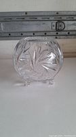 Crystal glass dish, clear with intricate cut designs, shown from front angle.