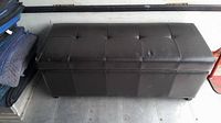 Top and front view of a dark brown leather-like bench storage chest with tufted cushioned lid and stitched panels.