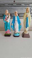Full view of all three Virgin Mary statues showing size and color variations