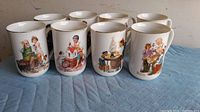 Front view of 8 ceramic mugs lined up, each with different Norman Rockwell painting art.
