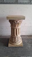 Full view of the plaster pedestal showing its ornate carvings and square top and base.