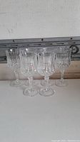 Front view of five of the crystal wine glasses arranged with some spacing showing the cut detail on the bowls and stems.