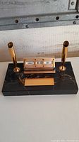 Full view of the vintage desk calendar and pen holder set showing black marble base, gold-tone double pen holders, calendar with rotating wheels, and blank plaque