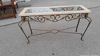 Side view of vintage metal and glass console table showing decorative scrollwork metal base and removable glass top.