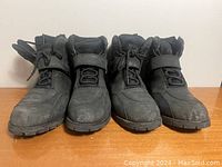 Front view of two pairs of black men's motorcycle boots in size 8 with visible wear and scuffs.