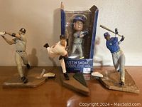 Three baseball figurines on a surface: two McFarlane figures and one boxed Justin Smoak bobblehead, showing lot contents.
